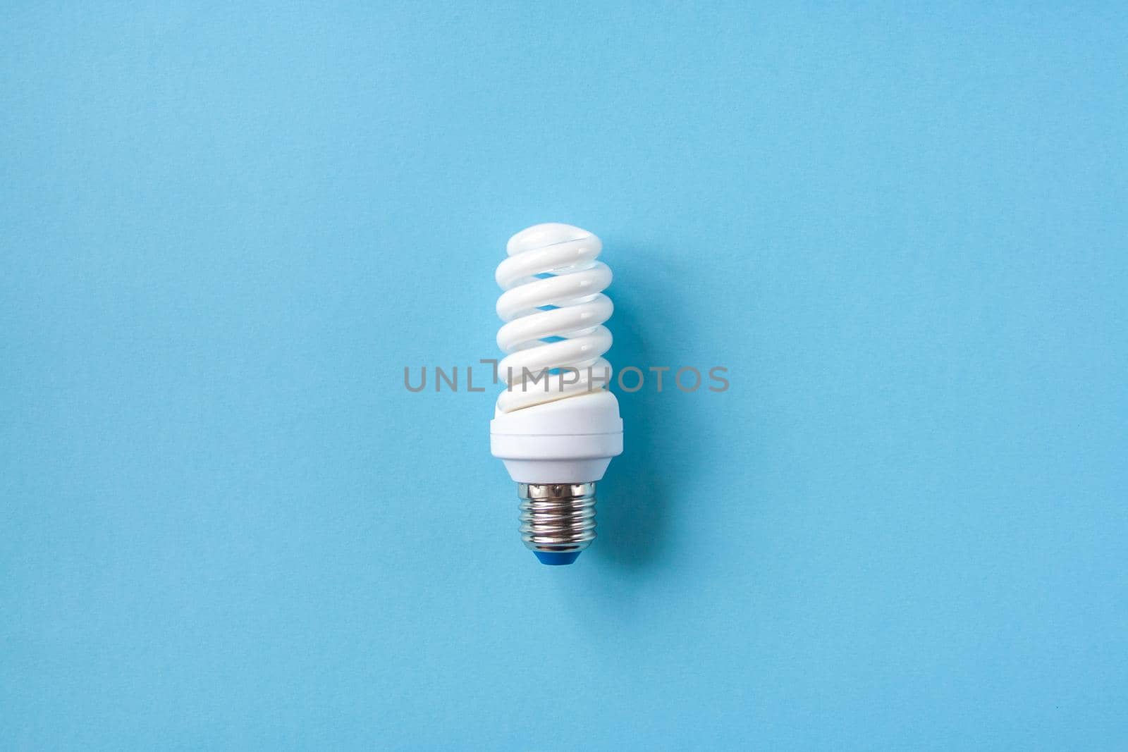 Energy saving light bulb on a blue background. Economical consumption of electricity. The concept of nature conservation