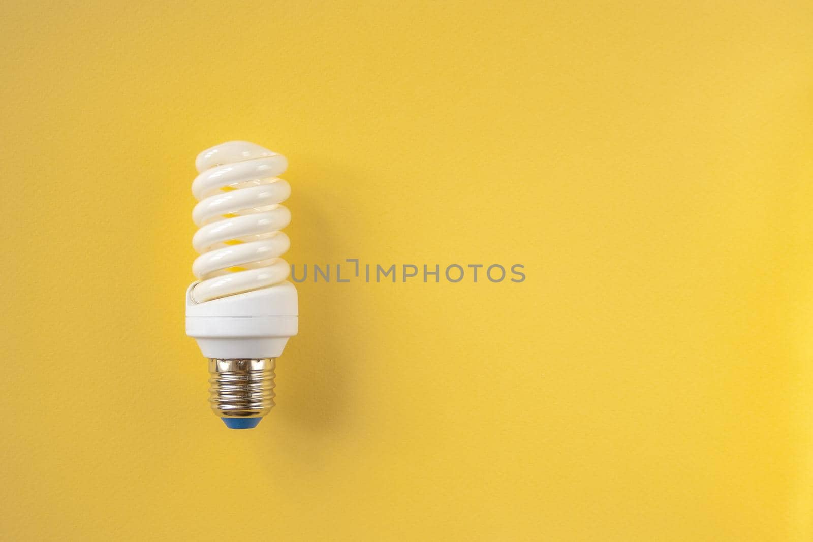 Energy saving light bulb on a yellow background. Economical consumption of electricity. The concept of nature conservation