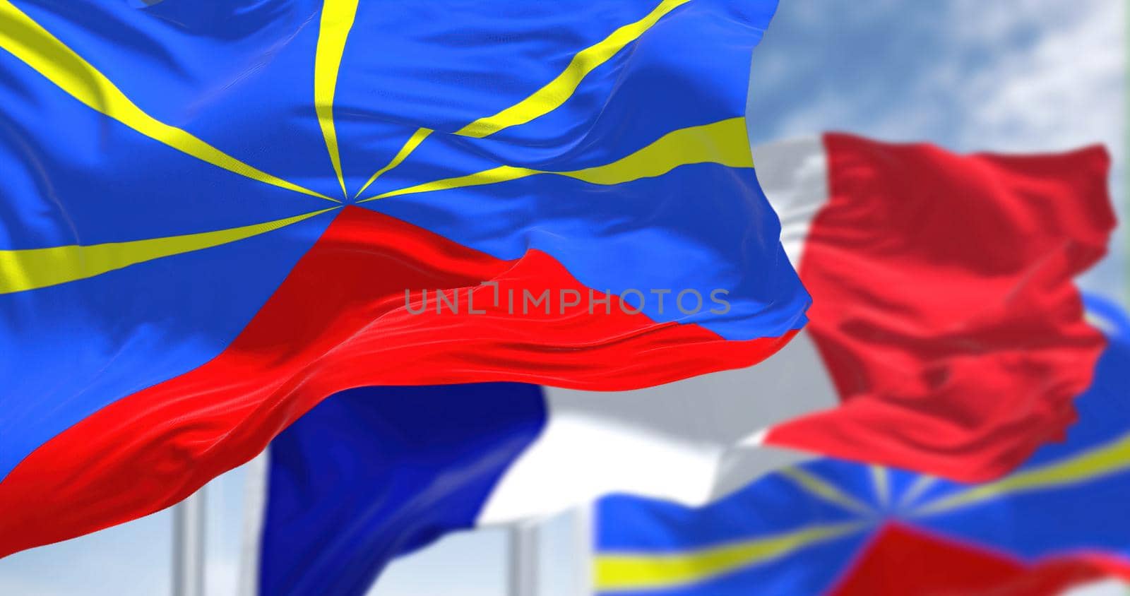 Flags of Reunion waving with the flag of France on a clear day. Reunion is an island in the Indian Ocean that is an overseas department and region of France