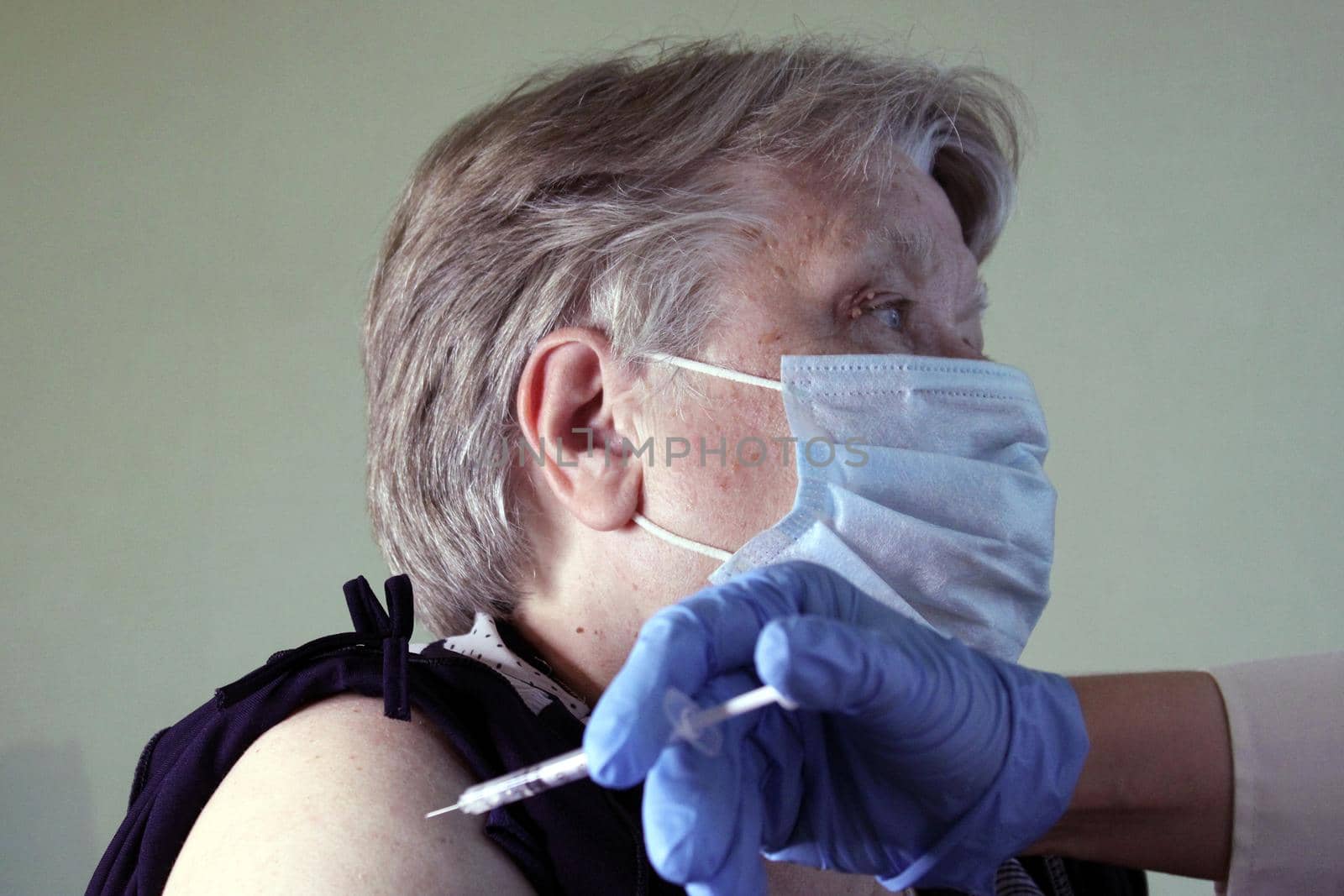 An elderly woman at the doctor's appointment is vaccinated. Syringe with vaccine close-up. The concept of vaccination against Covid19..