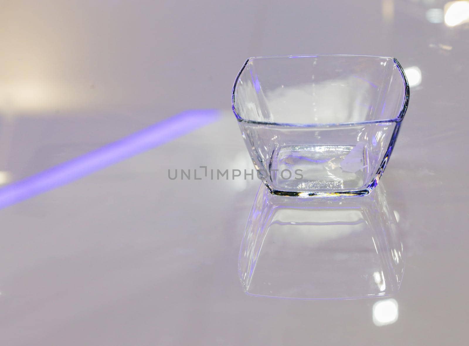 An empty clear and transparent glass ashtray on a glass table. by gelog67