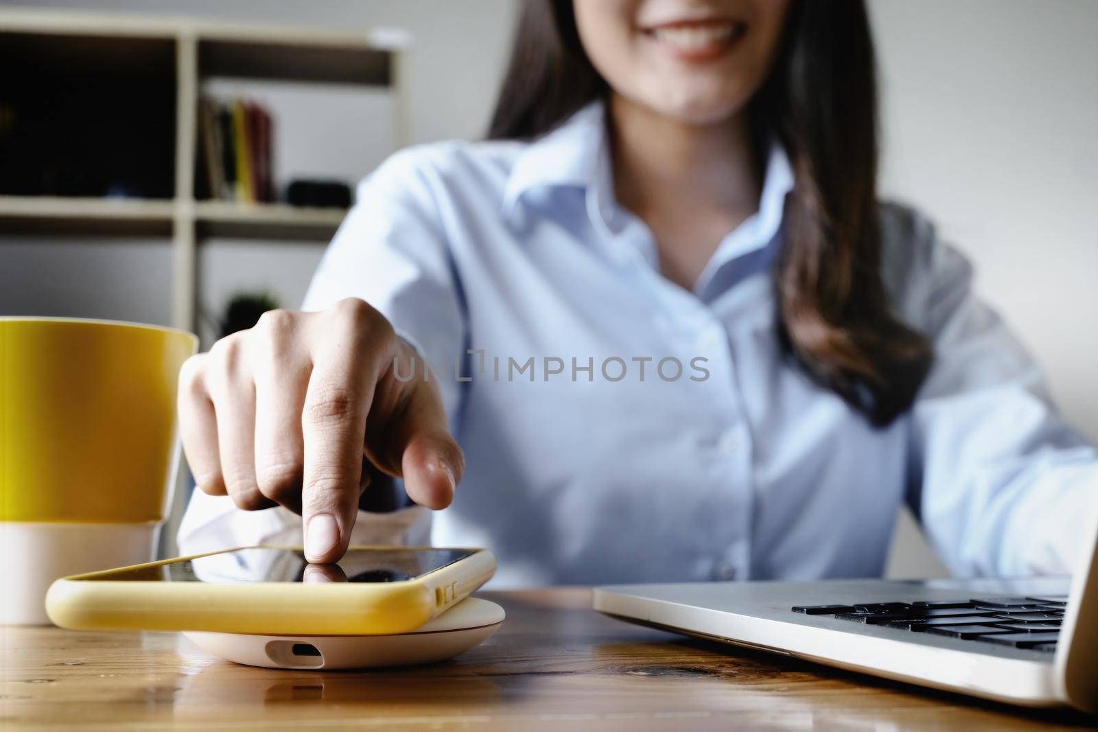 focus Female hand holding Smartphone to Charging at Wireless fast Charging pad at work. vintage tone. by Manastrong