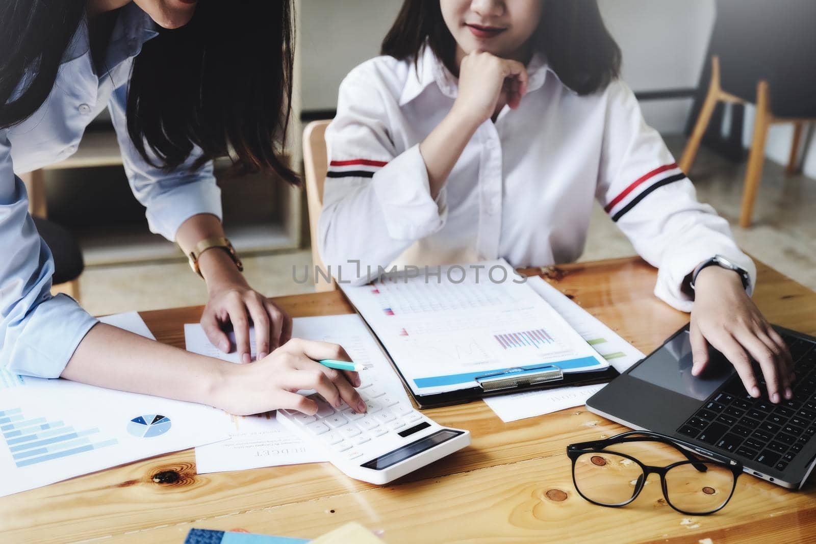 focus hand using calculator, Two young business executives are discussing to change their business concept to increase profits and the strength of their business with using calculator for work. by Manastrong