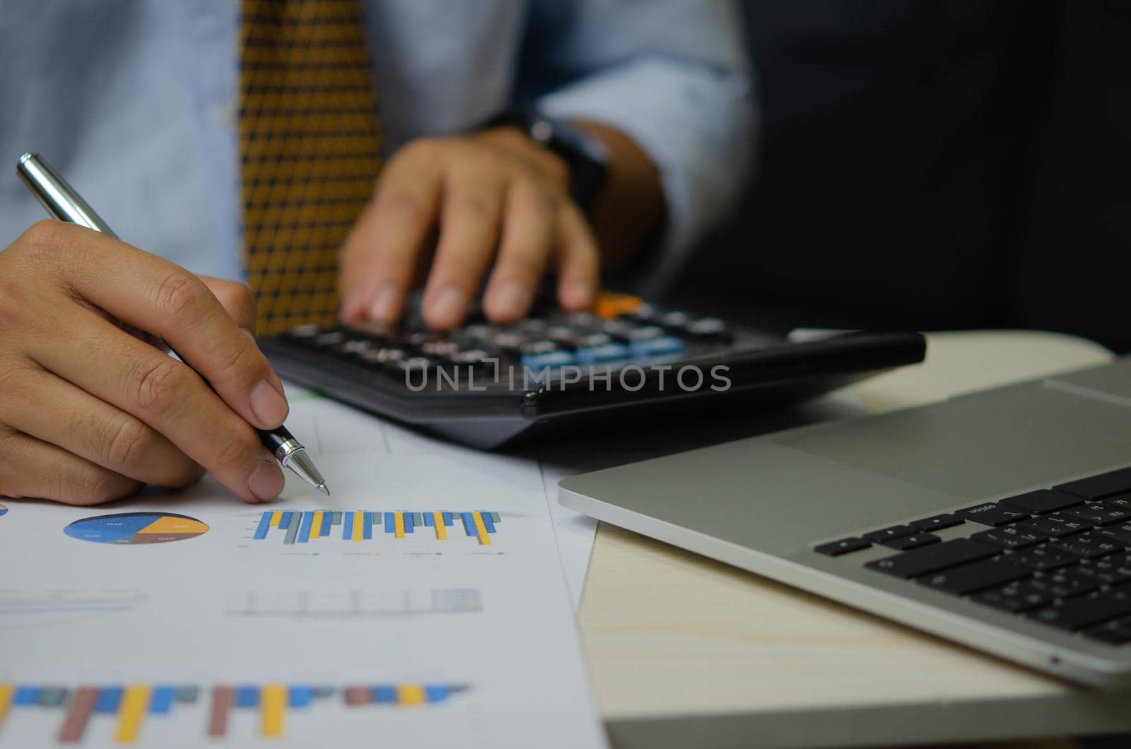 businessman hand pen with graphs and charts business documents calculator and computer laptop.Financial and tax marketing business concept.