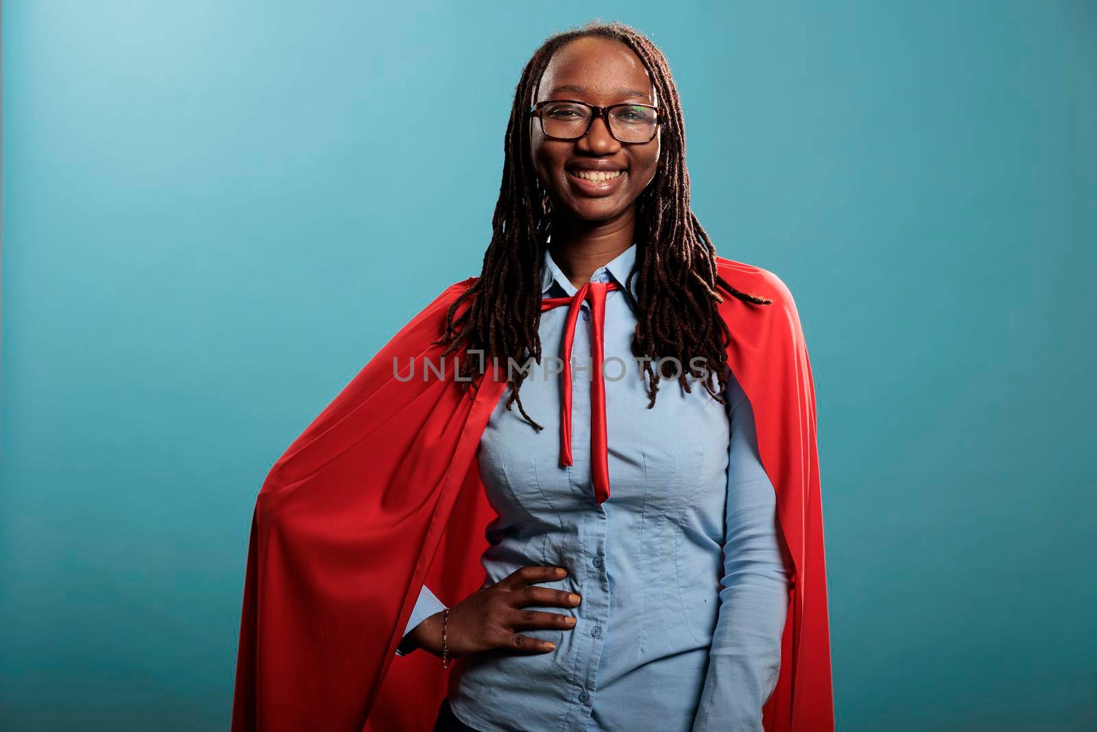 Portrait of brave young adult superhero woman wearing justice defender red cape by DCStudio