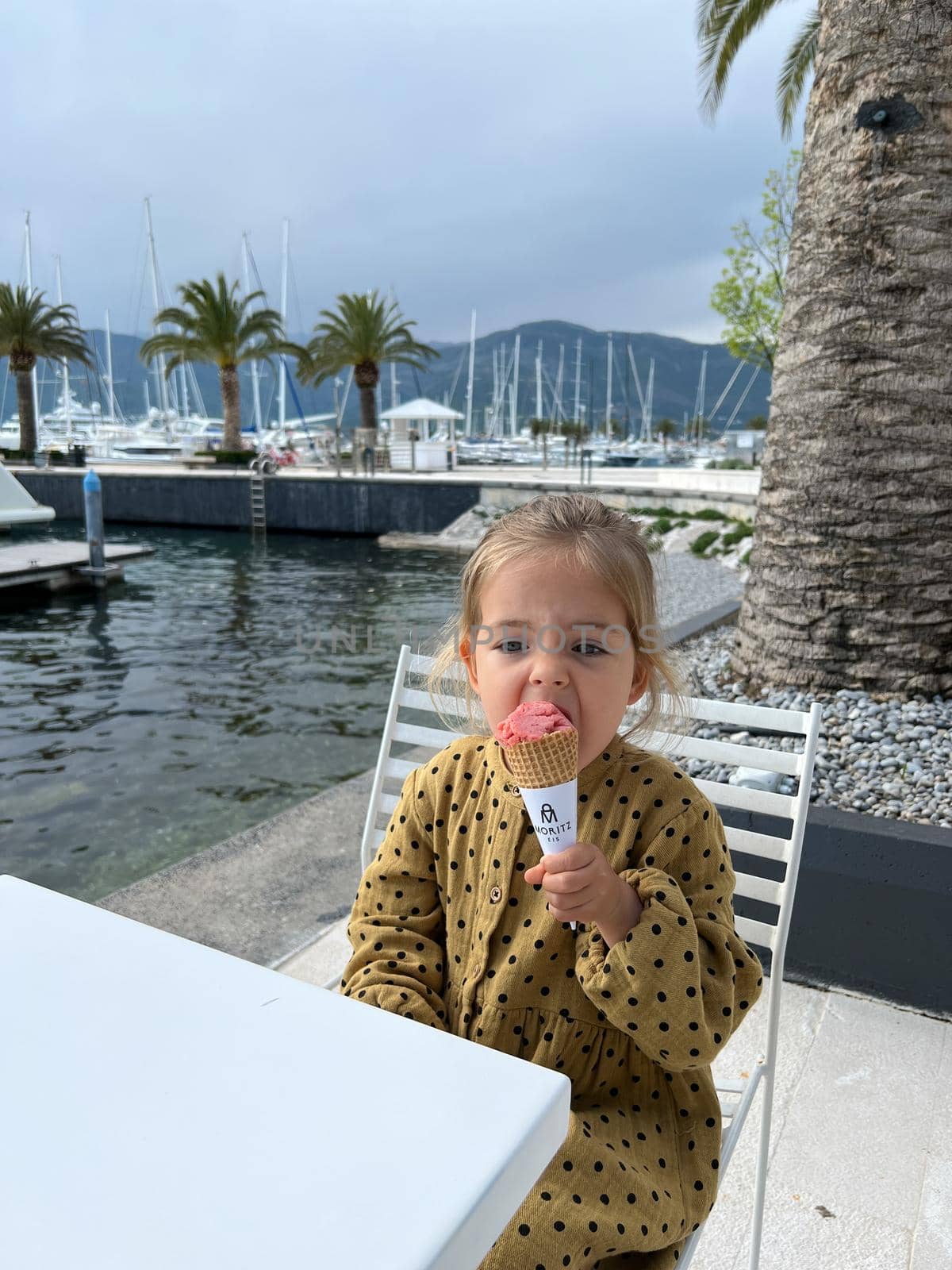 Little girl eats an ice cream cone on the embankment. High quality photo