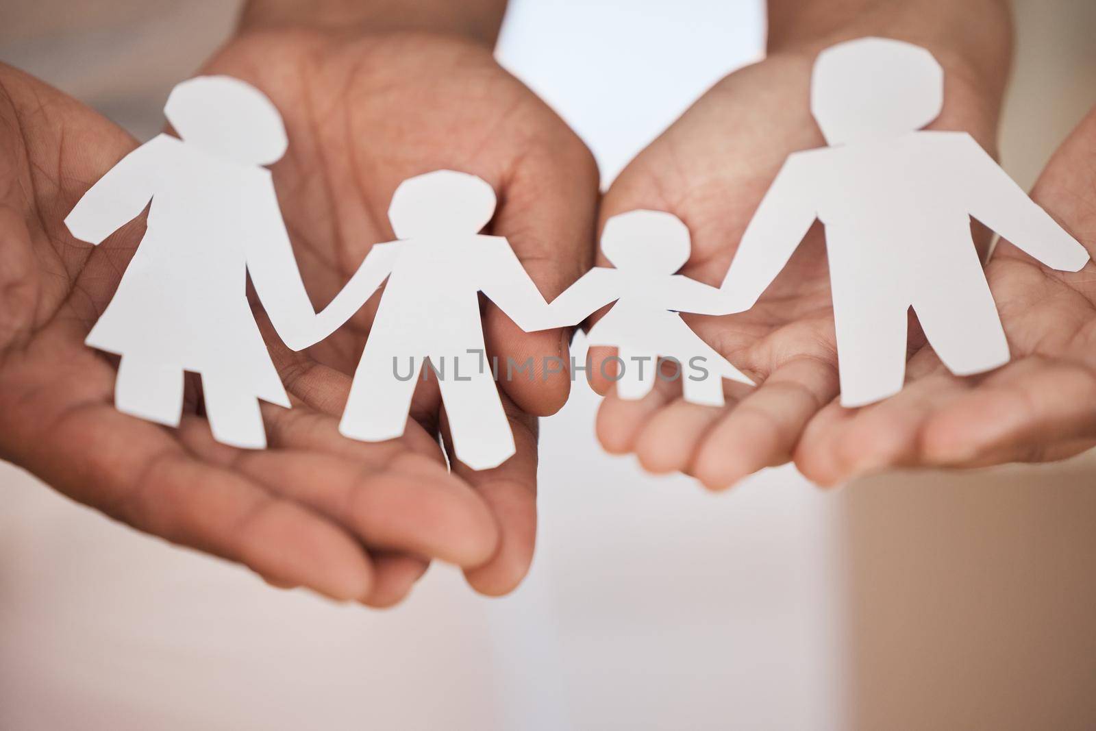 Closeup of a couples hands holding paper cutout of a perfect family. Symbol of home cover, insurance, health, adoption, custody, law, safety, security protection, foster, adoption family home concept by YuriArcurs