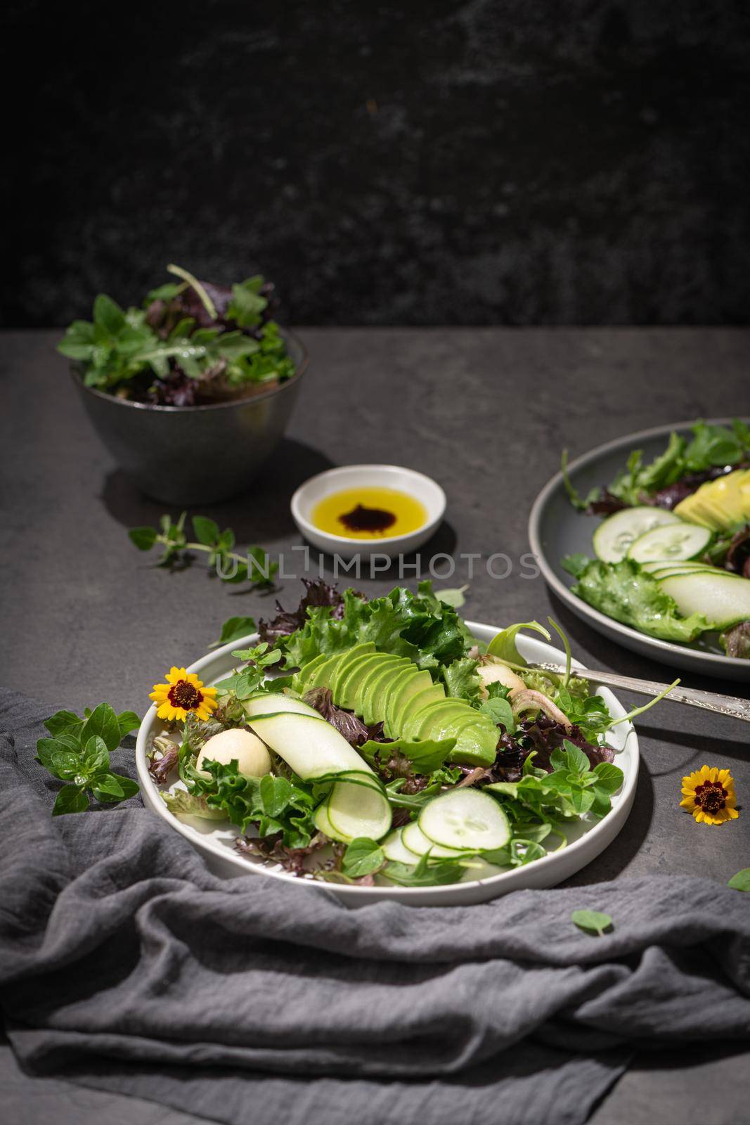 Fresh summer salad with cucumber, melon, avocado and fresh oregano served on ceramic plates.