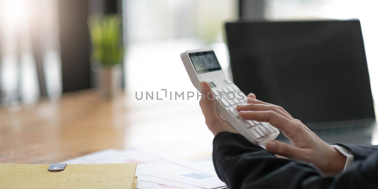 Close-up of business woman hands using a calculator to check company finances and earnings and budget. by wichayada