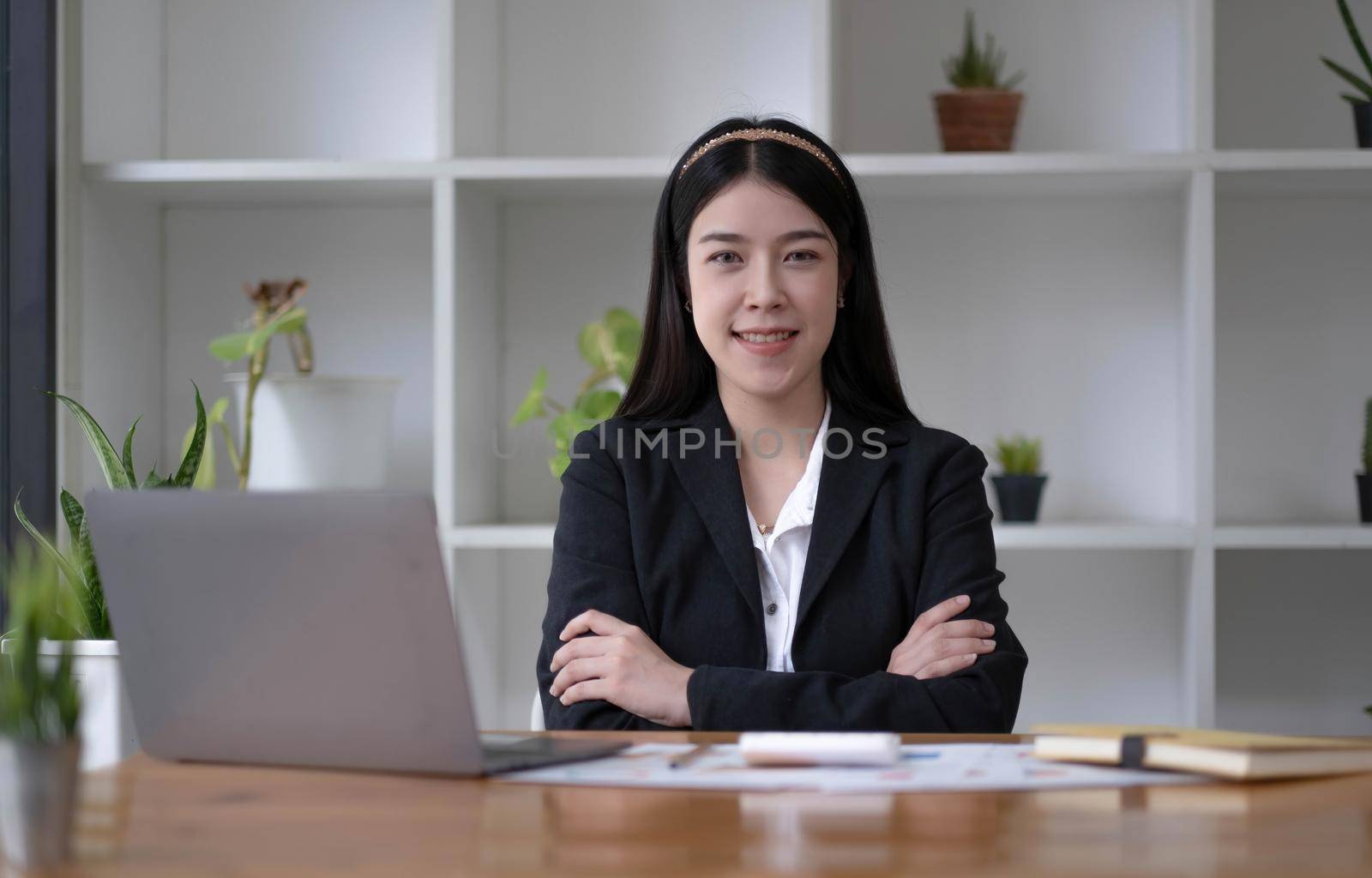 Charming Asian woman working at the office using a laptop Looking at the camera. by wichayada