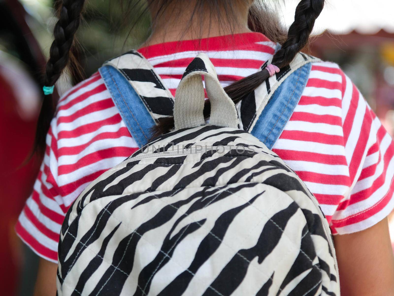 Rear view of happy smiling little girl with backpack getting in the car to ride to school. Little girl is happy and ready to learn. Back to school. by TEERASAK
