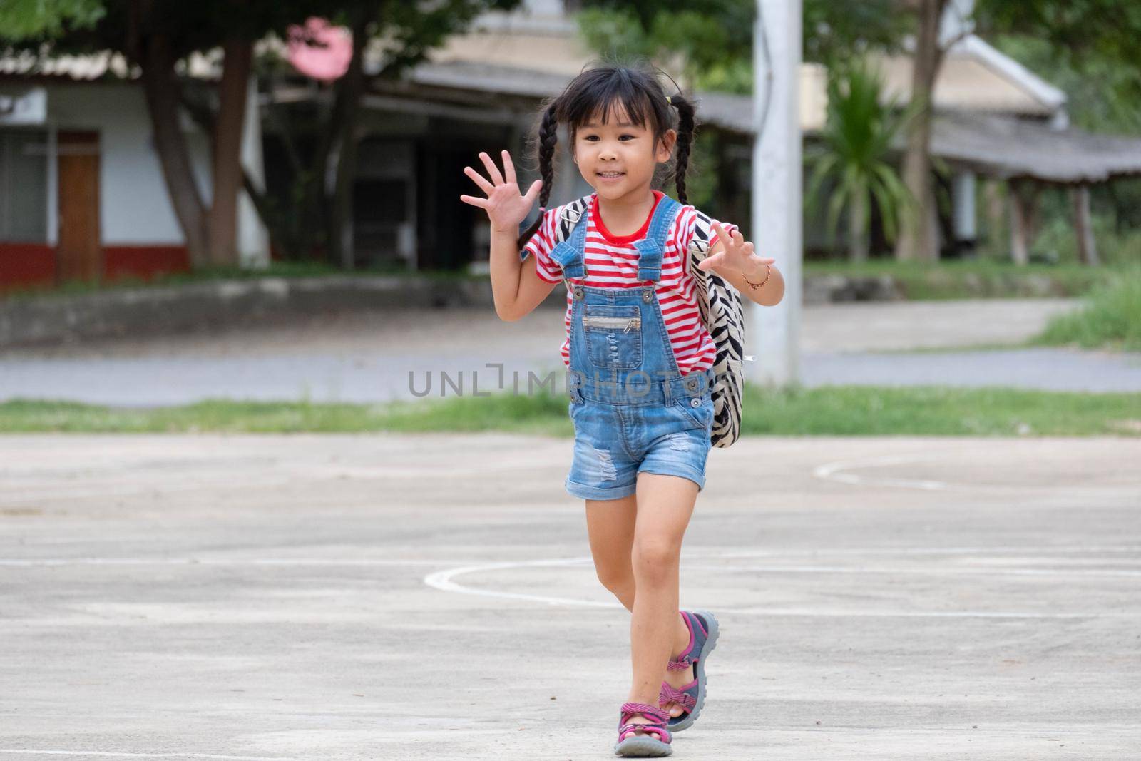 Happy smiling little girl with backpack running to school for the first time. Little girl is happy and ready to learn. Back to school. by TEERASAK
