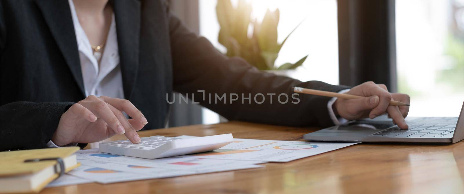 Close-up of business woman hand using a calculator and take notes to check company finances and earnings and budget. by wichayada