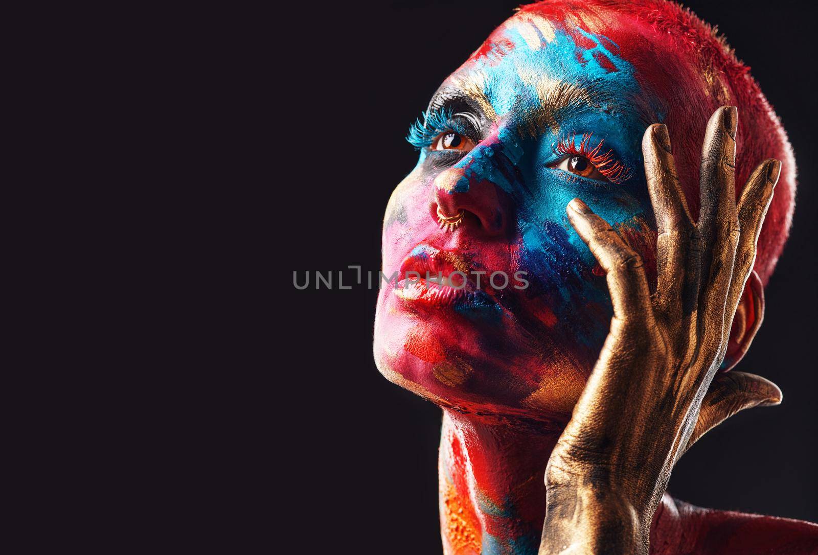 I choose my uniqueness, always. an attractive young woman posing alone in the studio with paint on her face. by YuriArcurs