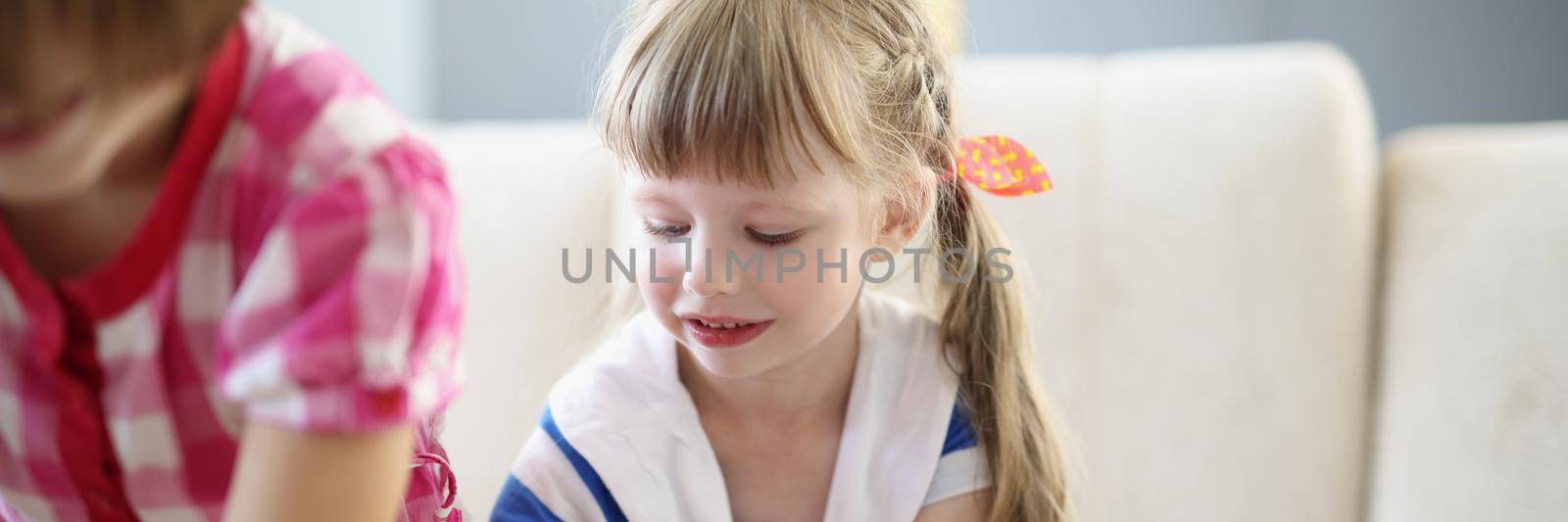 Portrait of little blonde girl busy with playing card game on table at home. Funny pastime for children and development. Childhood, holiday, fun concept
