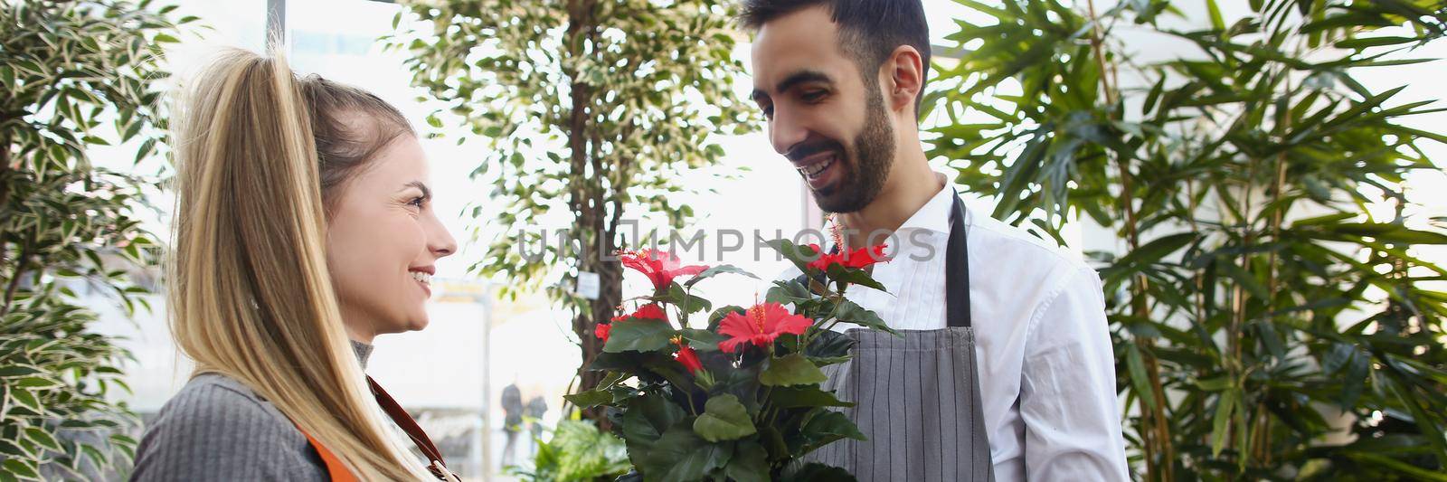 Man consultant gives flowers in pot to his colleague, show liking for her by kuprevich