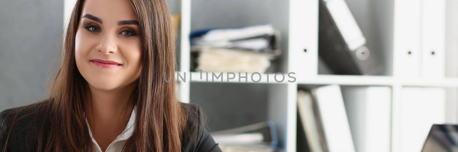 Attractive worker in suit holding cup of coffee, posing on working place in office by kuprevich