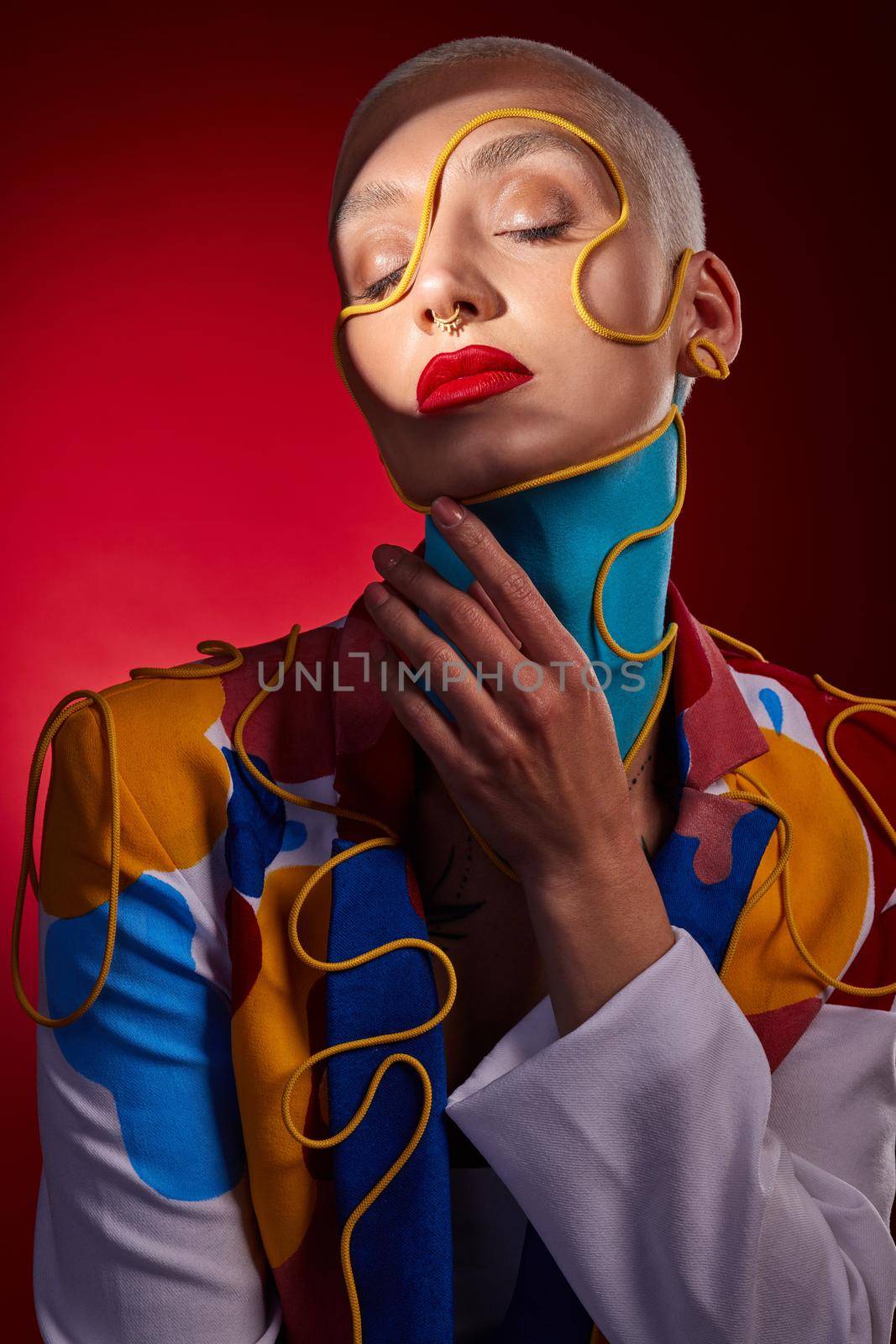 Accessorise and colorise. Studio shot of a stylish young woman posing against a red background. by YuriArcurs