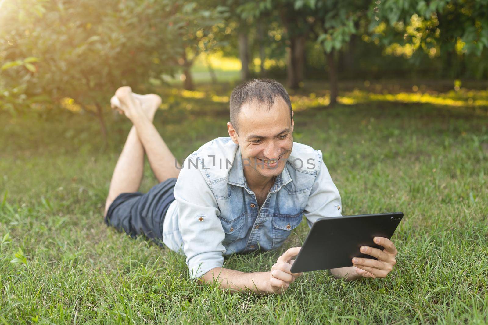 a man uses a tablet to chat in the garden by Andelov13
