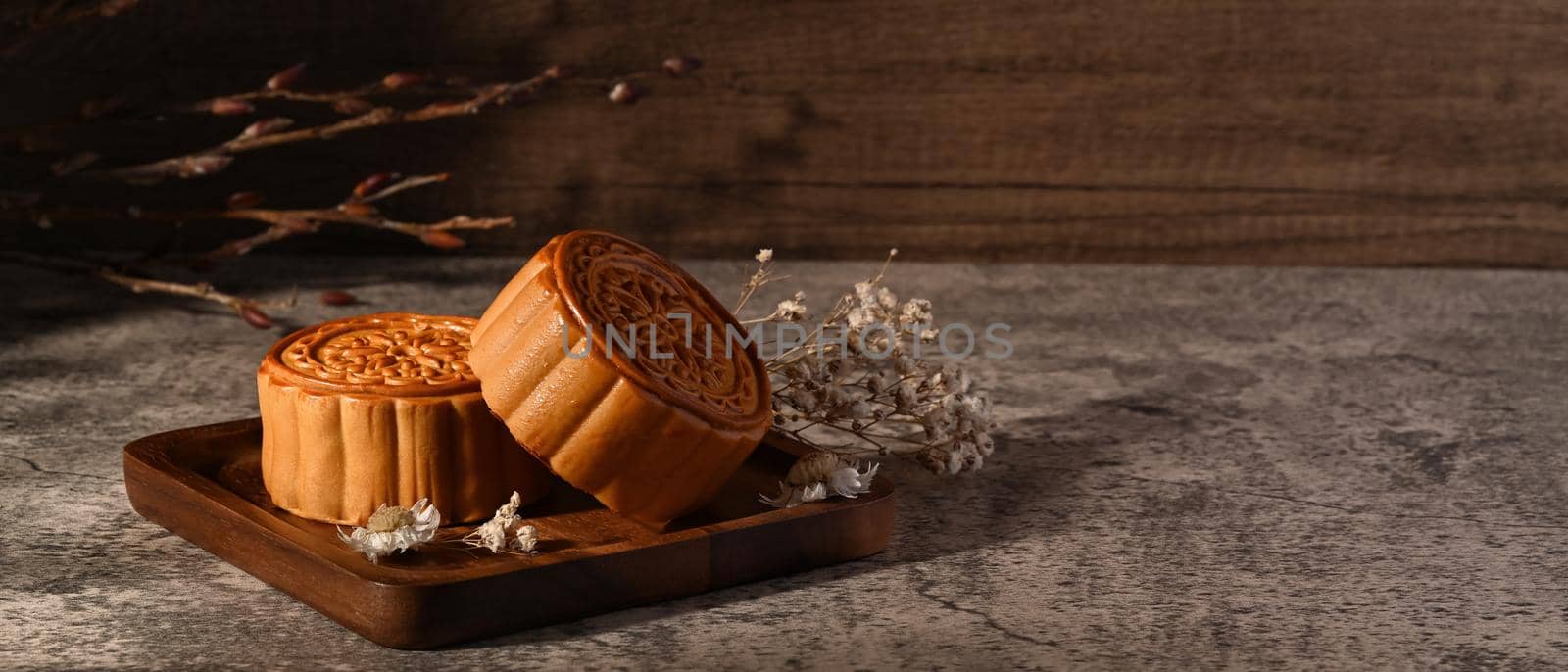 Tasty Chinese mooncakes decorating with dried flower on grey stone background. Chinese Mid autumn festival celebration.