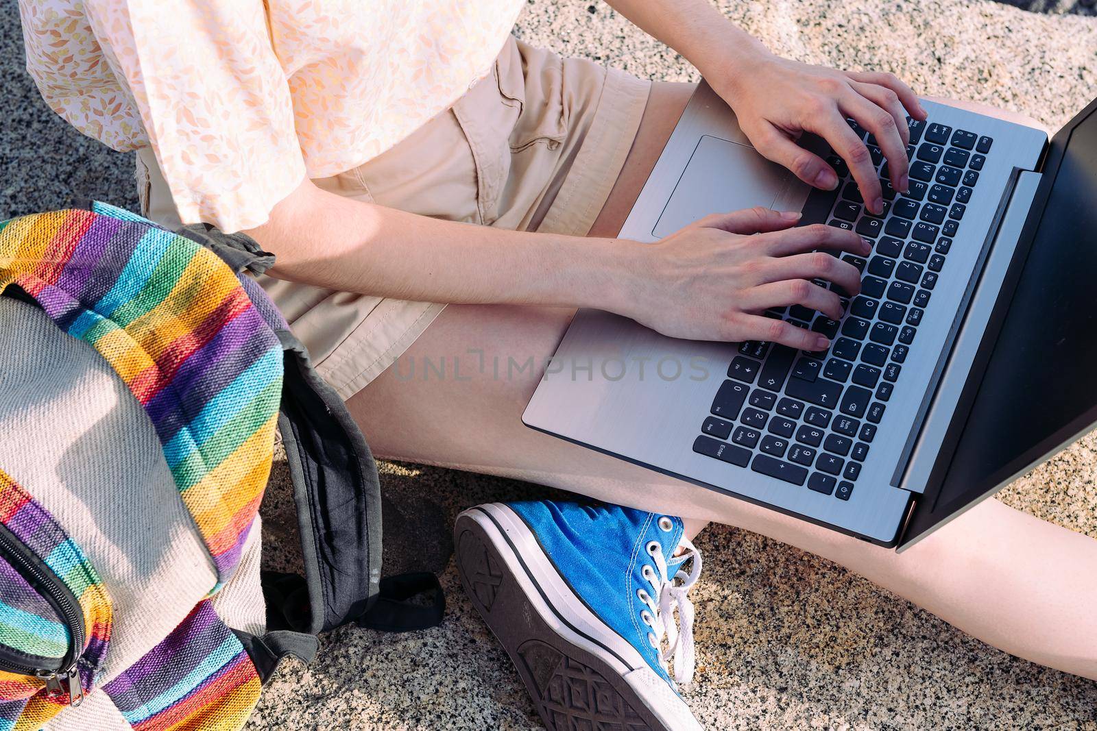 hands of an unrecognizable young traveler girl working with a laptop outdoors, concept of digital nomad and blogger lifestyle