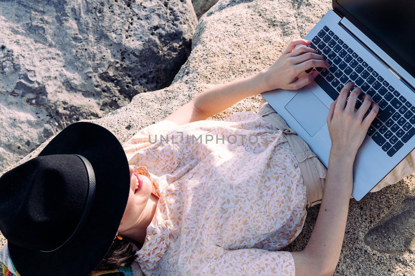 young woman typing lying down with laptop outdoors by raulmelldo
