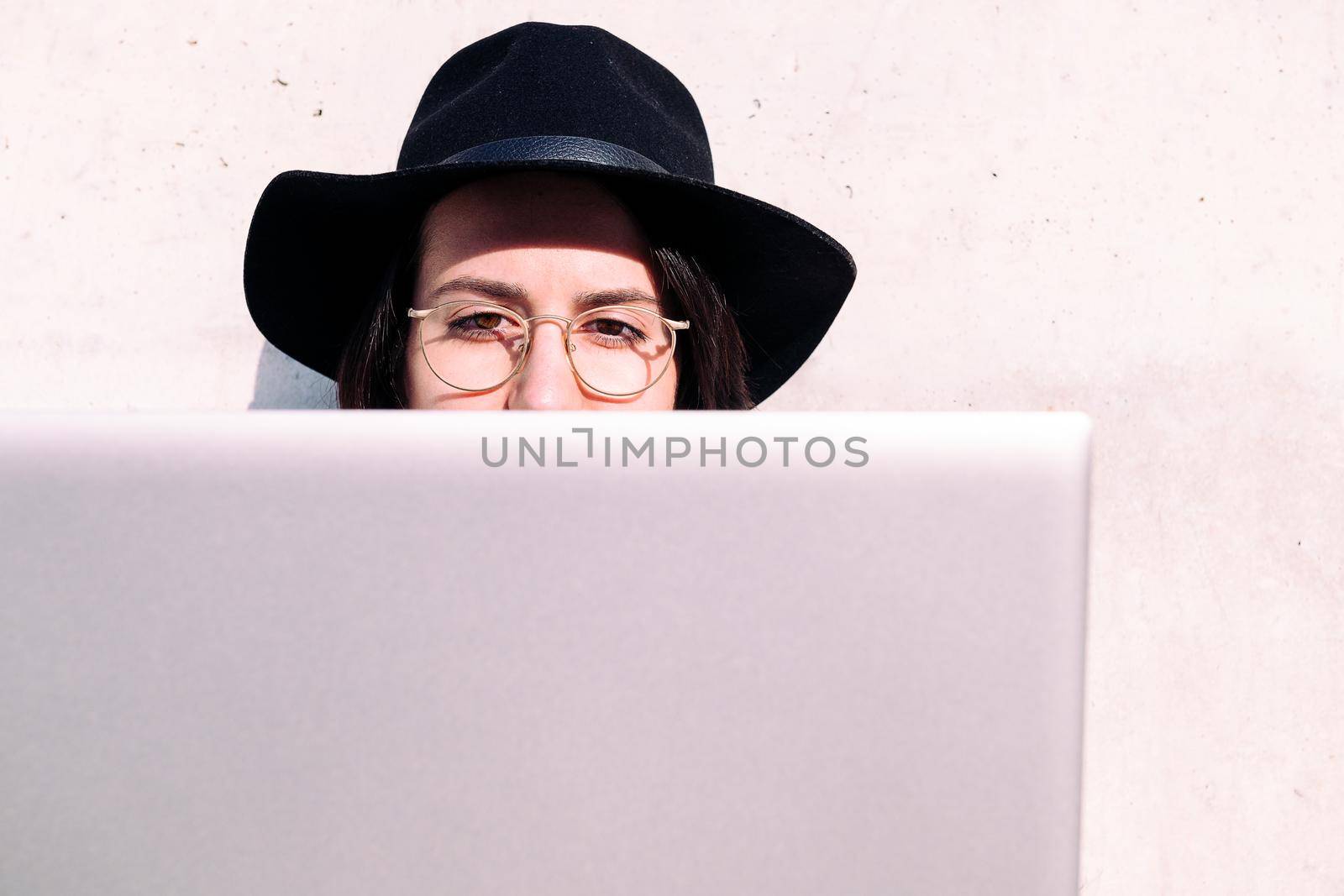 eyes of a young woman working with laptop sitting against a grey wall, concept of digital nomad and blogging lifestyle , copy space for text