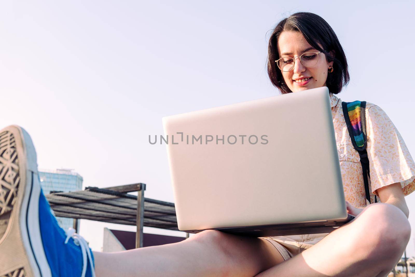 young woman working in the city with her computer and backpack, concept of technology, youth and digital nomad lifestyle, copy space for text