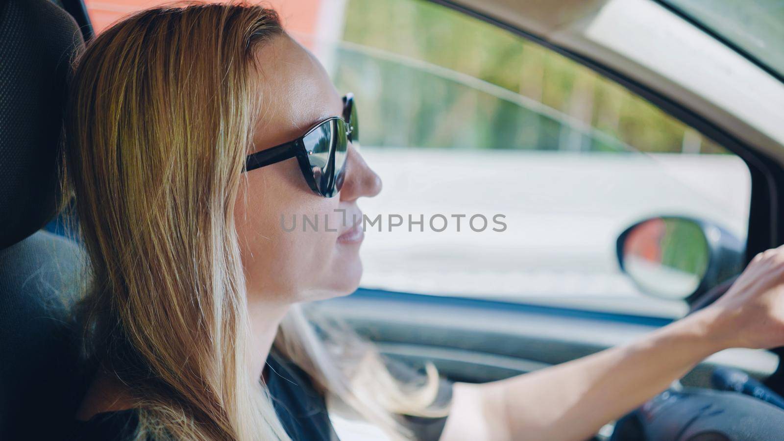 A young woman in a good mood behind the wheel of a car