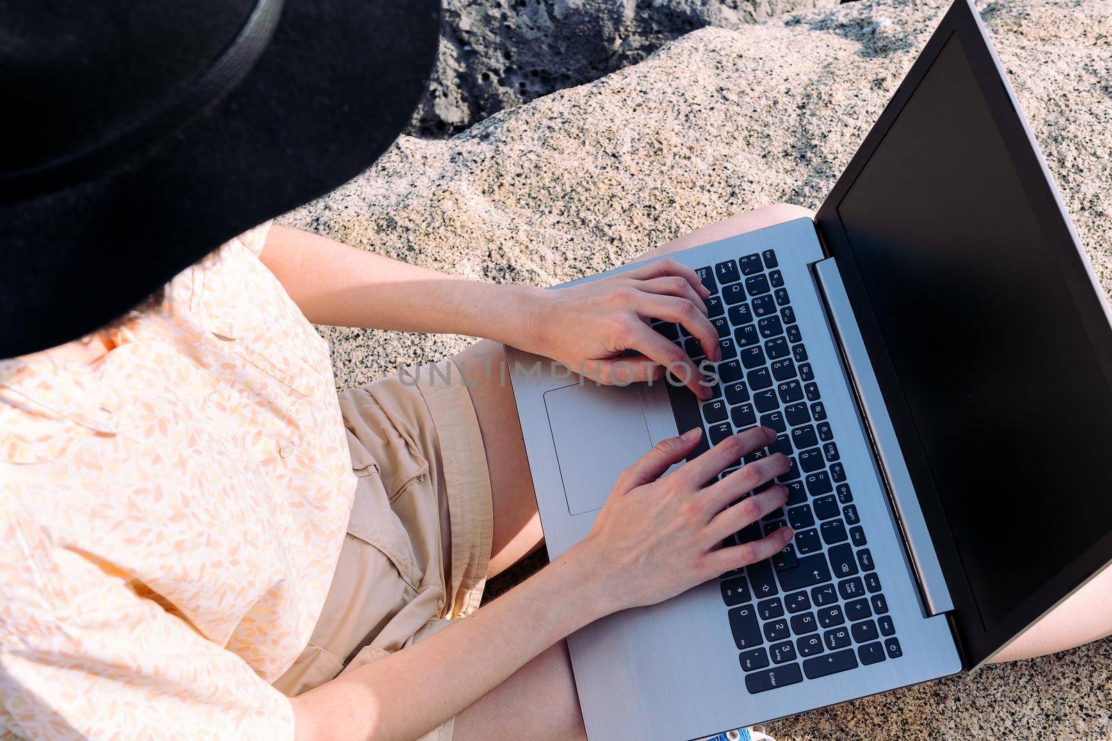 top view of the hands of an unrecognizable young traveler woman typing in a computer outdoors, concept of digital nomad and blogger lifestyle