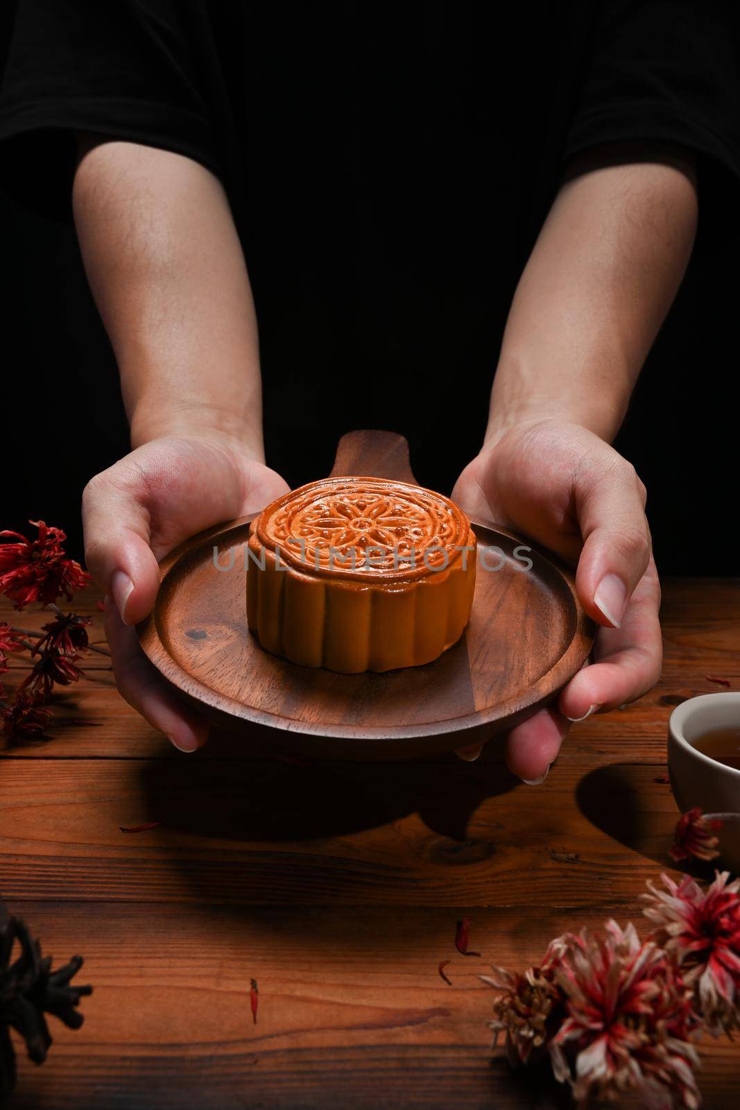 Hands holding wooden tray with Chinese traditional mooncakes. Mid Autumn festival and Chinese traditional festival.