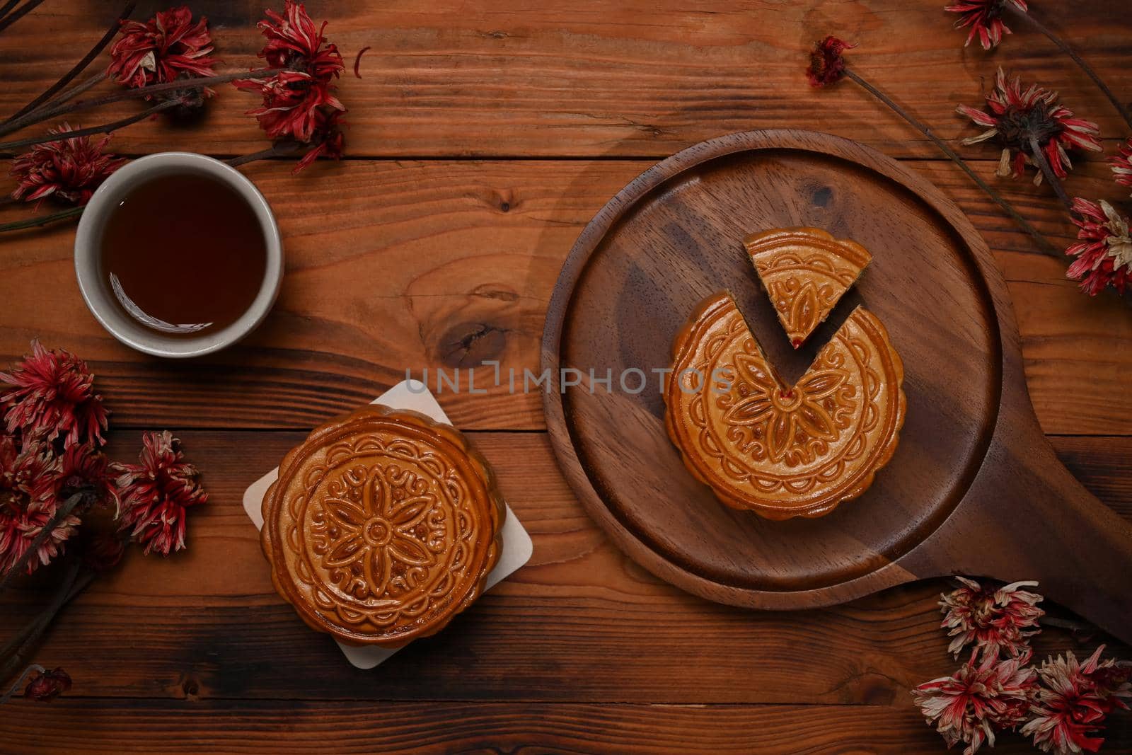 Top view, Traditional Chinese mooncakes, tea and dried flower on rustic wooden background.