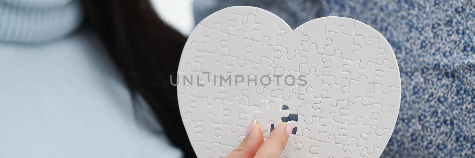 Woman fill empty space with missing piece of white heart puzzle, man holding it by kuprevich