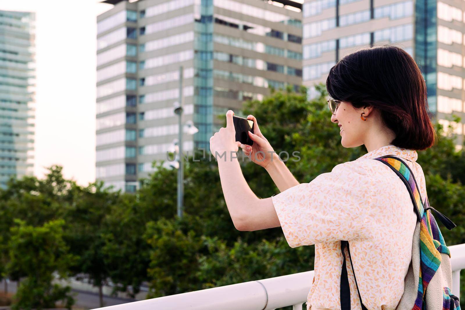 rear view of a young tourist woman taking a photo with the phone, concept of social media and traveler lifestyle, copy space for text