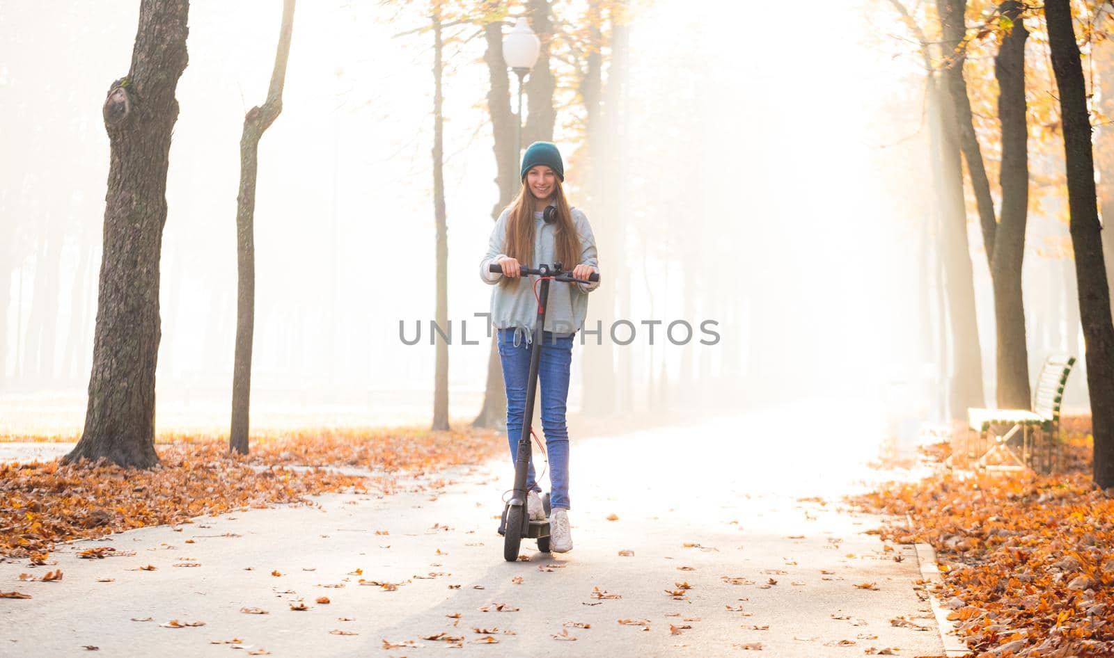 Cute teenage girl on scooter in autumn park