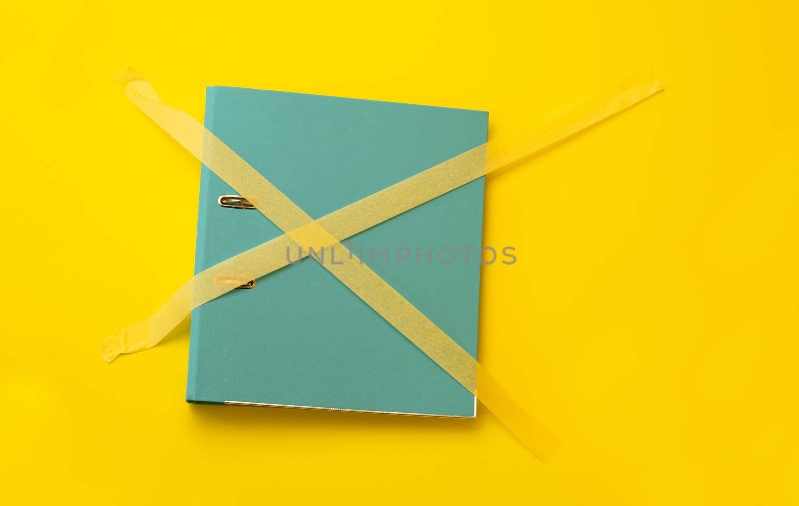 Folder sticked up with masking tape isolated on yellow background with copyspace. Concept of forbidden knowledge, security and safety of information