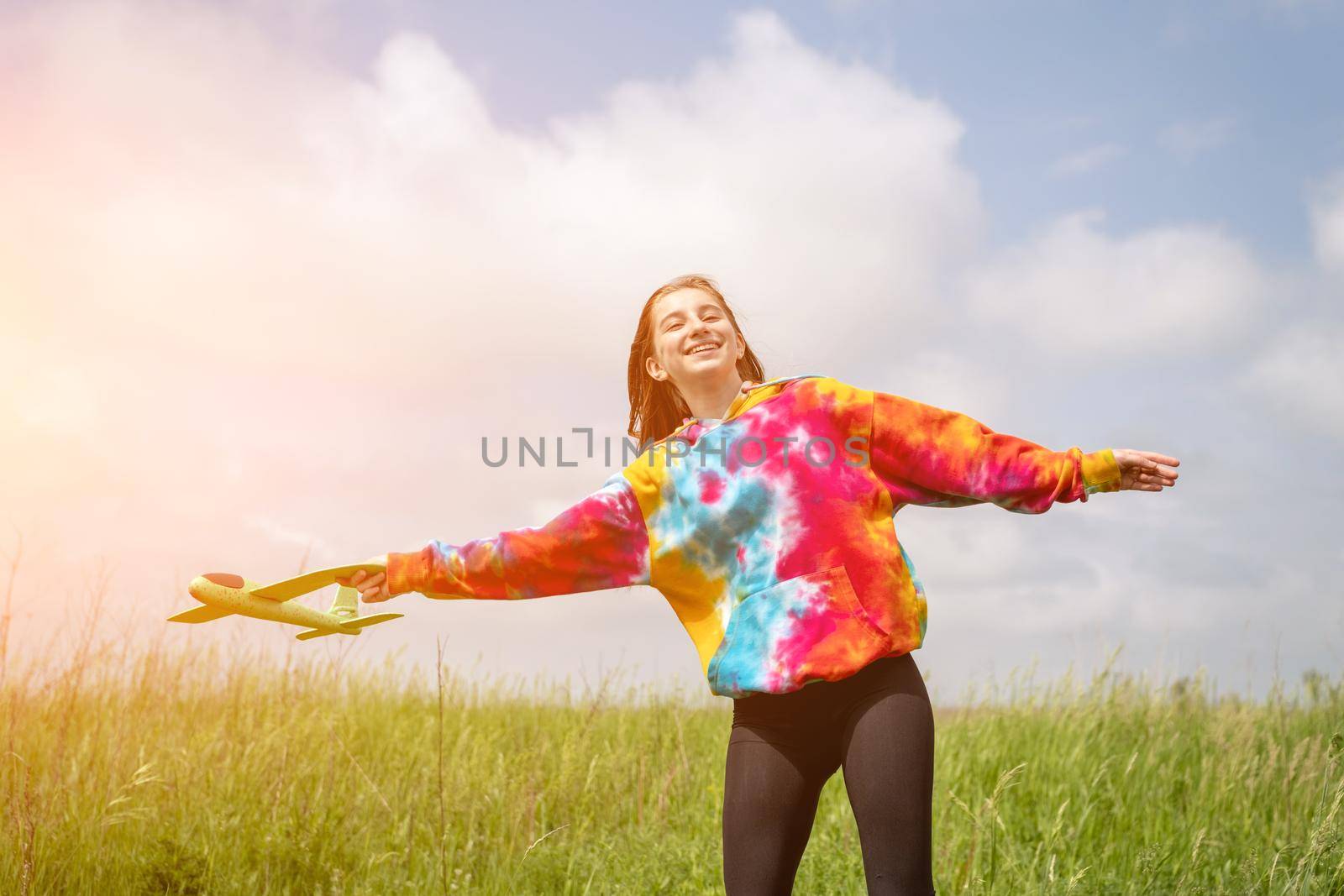 Beautiful girl playing with toy plane outdoors in the field. Teenager female person launching airplane at the nature. Concept of freedom and imagination