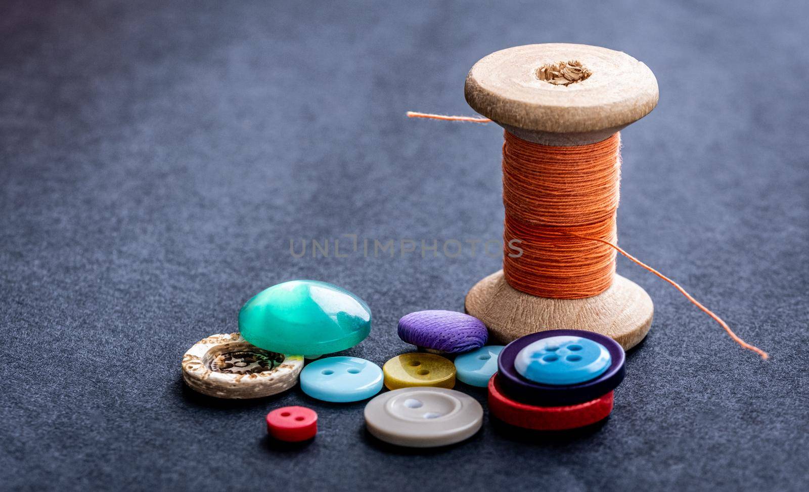 Colorful sewing buttons and orange thread spool macro