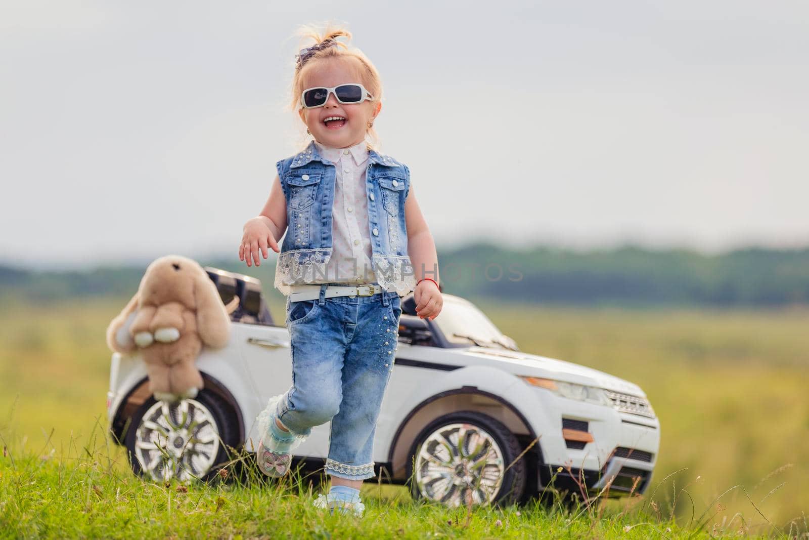 small child stands near his car on the lawn