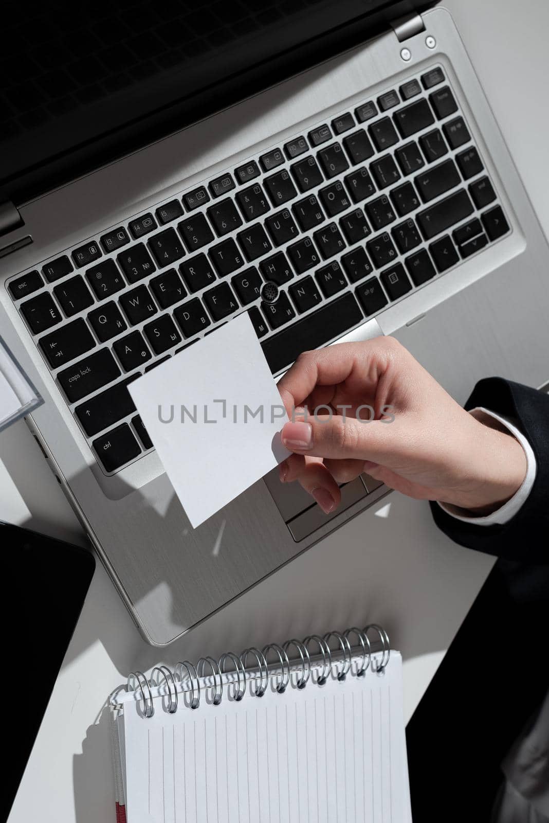 Buisnesswoman Holding Sticky Note With Important Message Over Lap Top And Notebook On Desk. Woman In Suit Presenting Crutial Information On Memo Above Computer And Notepad. by nialowwa