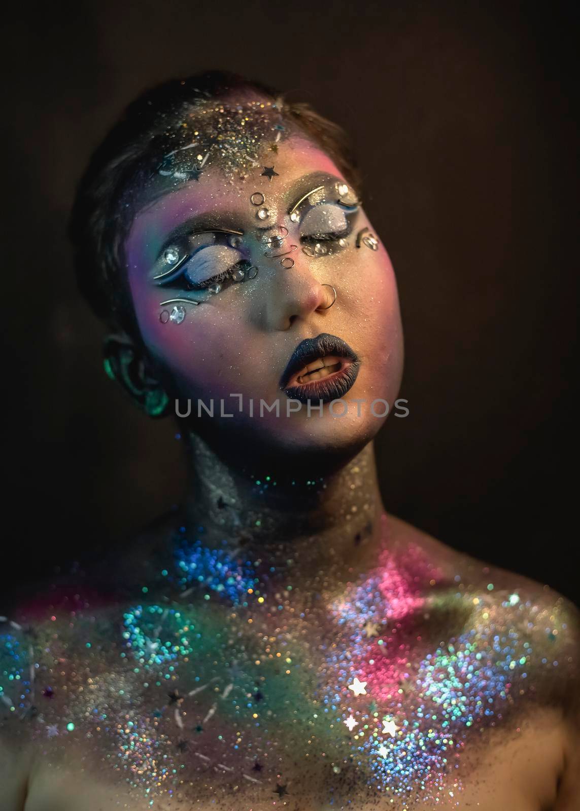 Portrait of young female model with creative makeup,  rhinestones and piercing