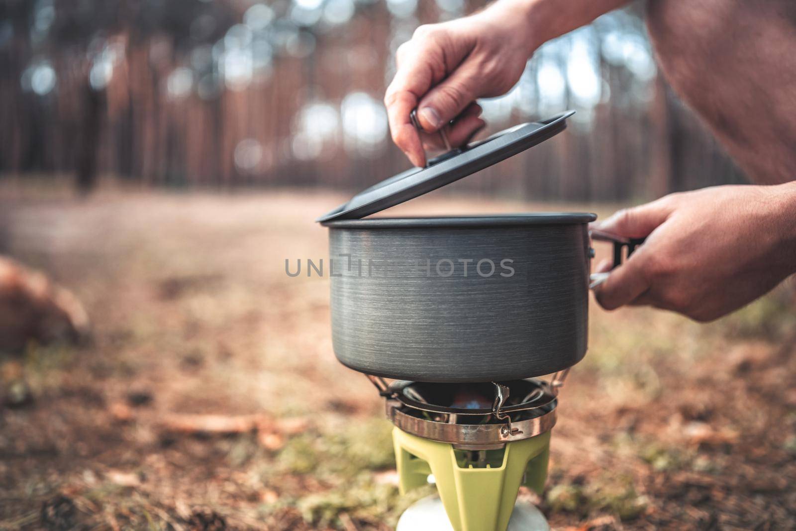 Cooking process in the camping in the wood with pan and gas equipment for food preparation. Picnic at the nature in the forest
