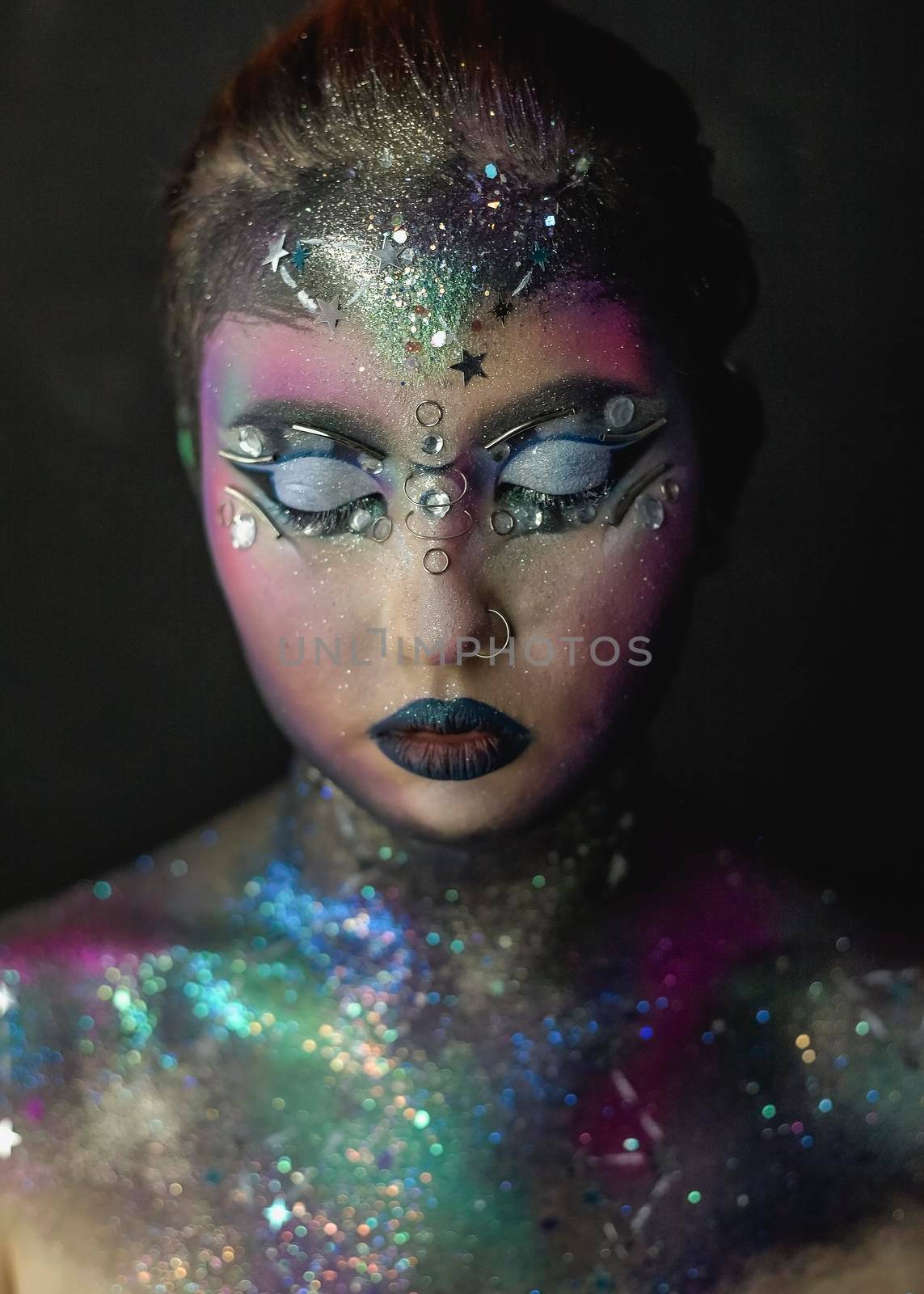 Portrait of young female model with creative makeup,  rhinestones and piercing