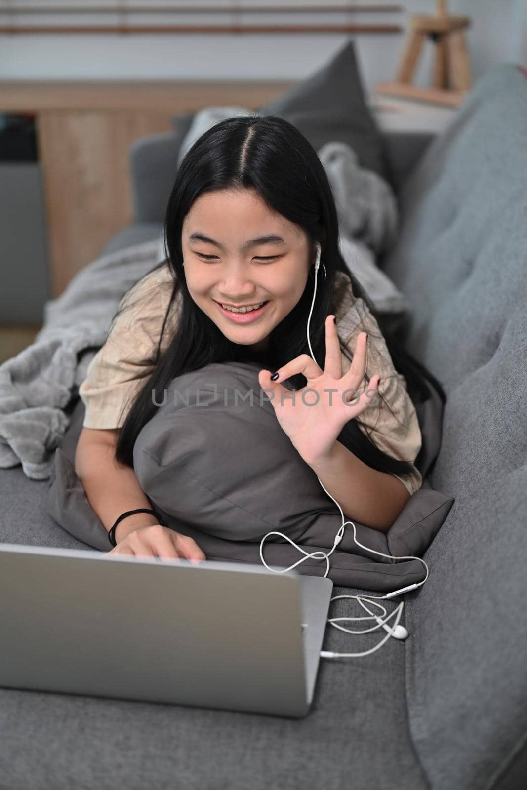 Smiling asian girl having video call on computer laptop at home. by prathanchorruangsak
