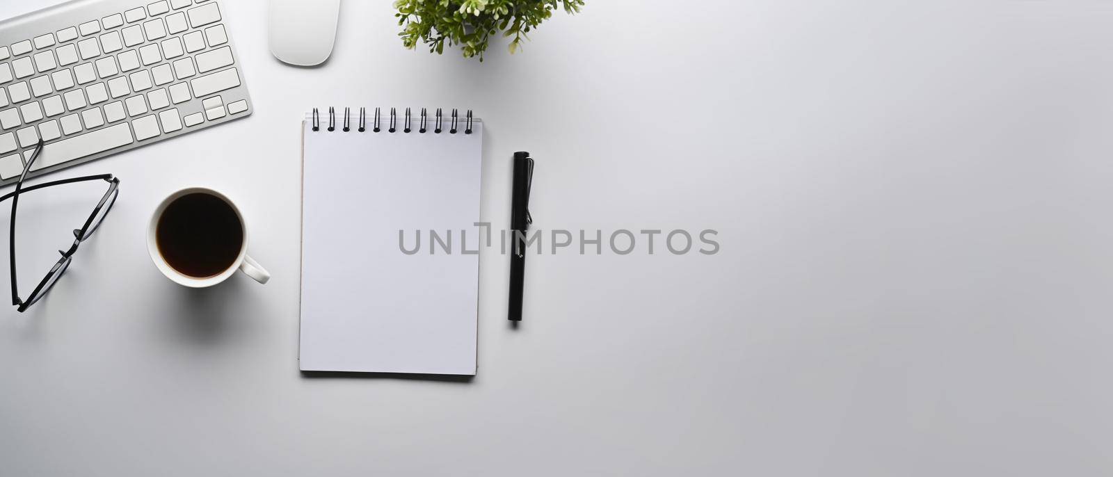 Top view empty notepad, coffee cup and potted plant on white table. Copy space.