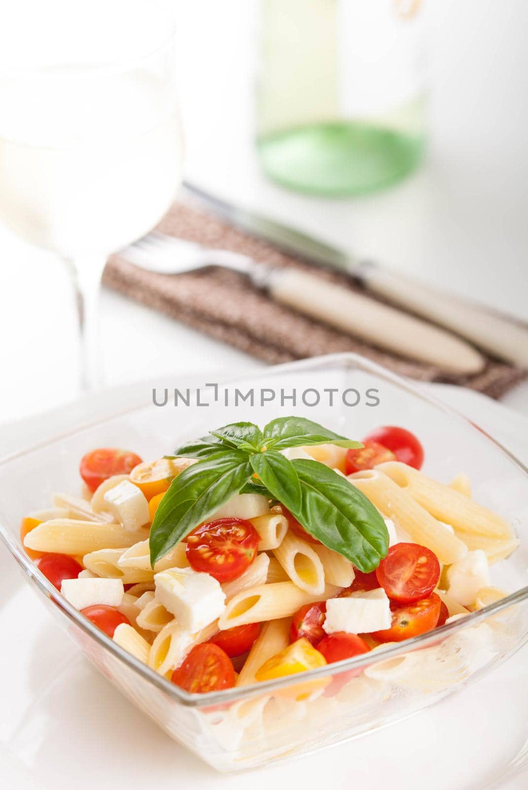 bright and tasty pasta salad with fresh mozarella and cherry tomatoes, basil