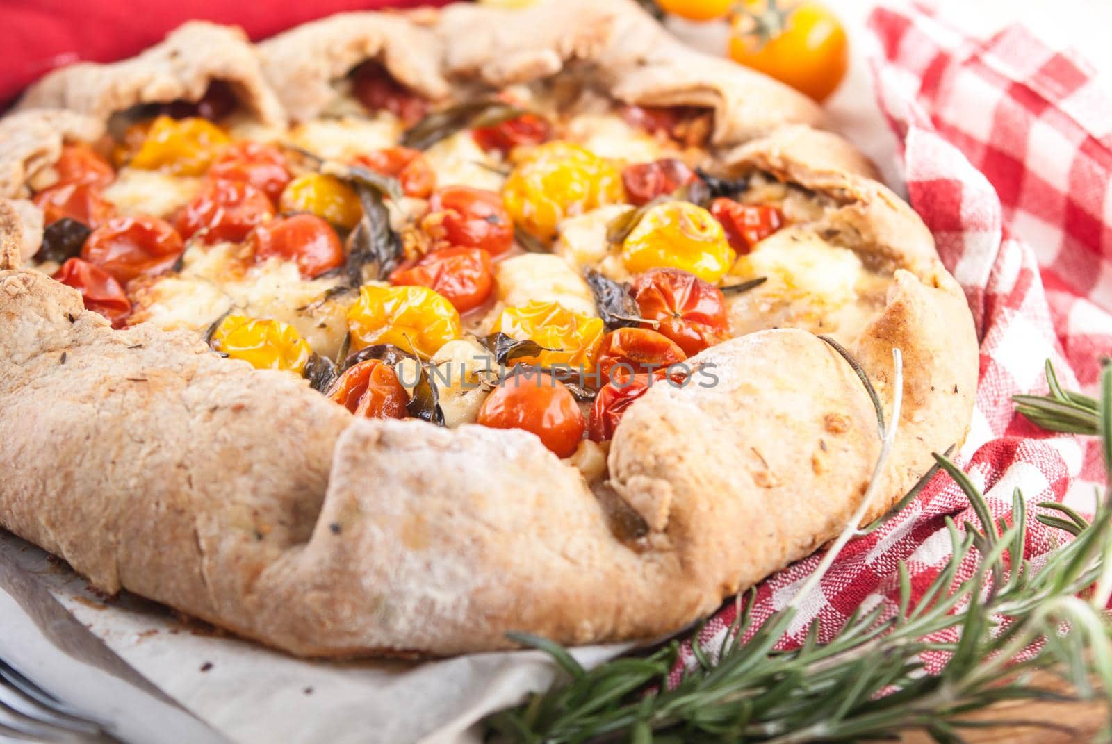 delicious homemade galetta pie with cherry tomatoes, feta cheese and basil and rosmarim herbs