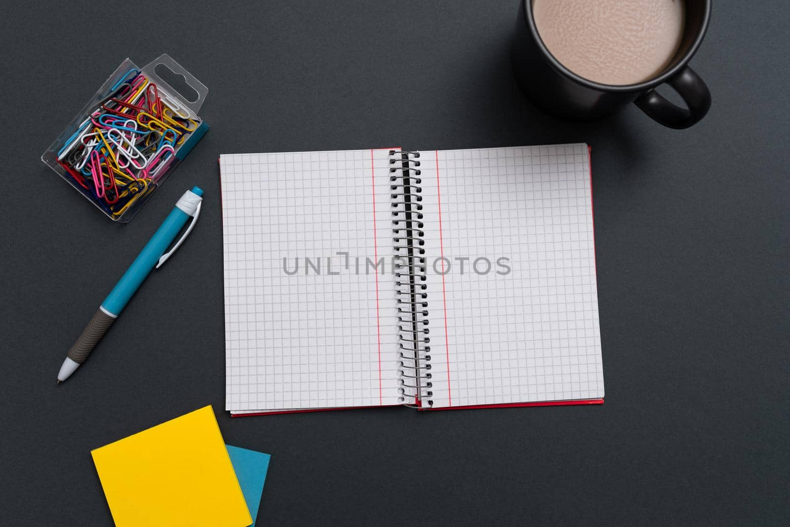 Notebook With Important Messages On Both Sides On Desk With Coffee, Pen, Paperclip And Memos. Crutial Information On Pad On Table With Cup And Pencil. Late Updates Presented. by nialowwa