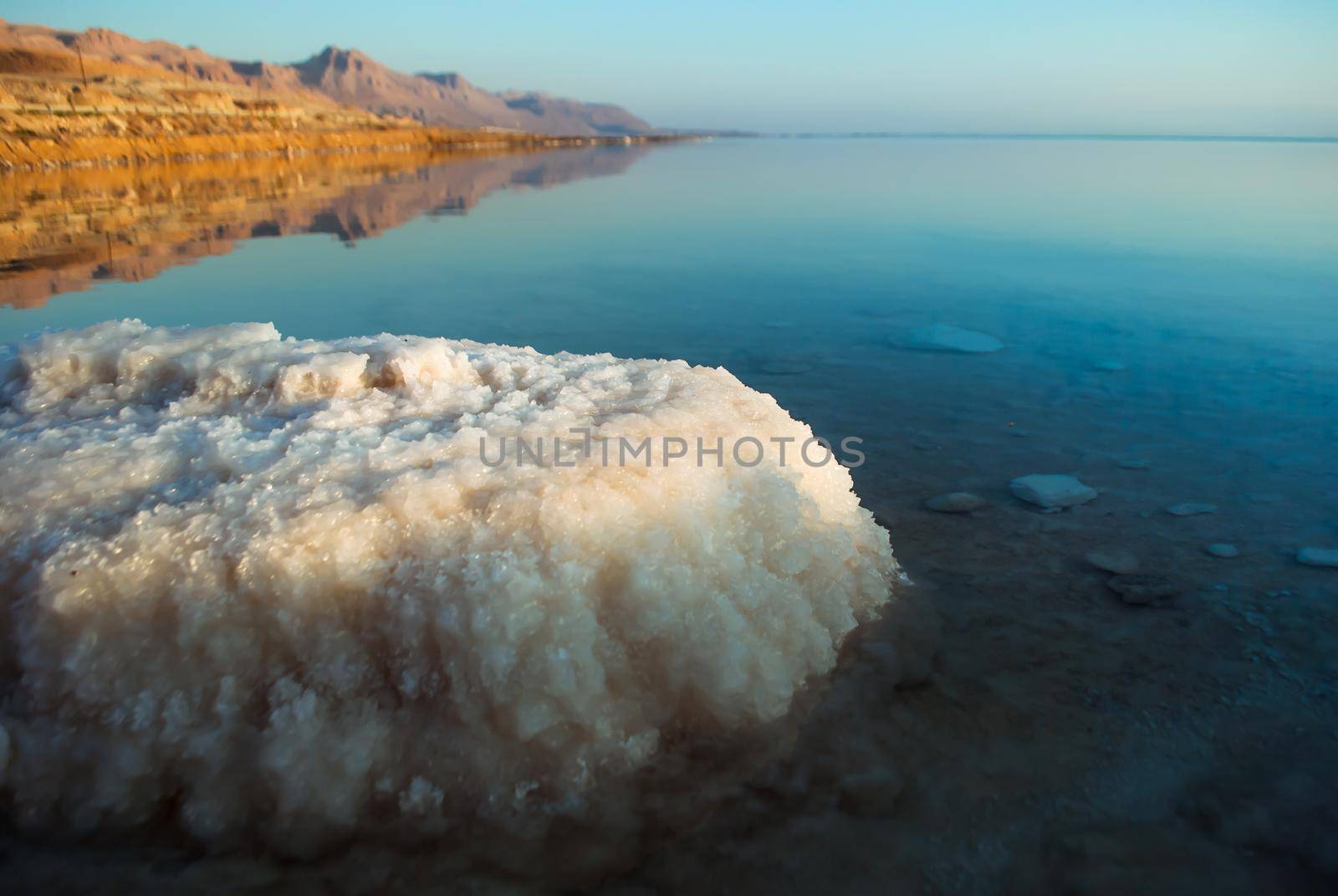 Beautiful sunrise at Dead Sea in Israel wih rocks of salt at foreground