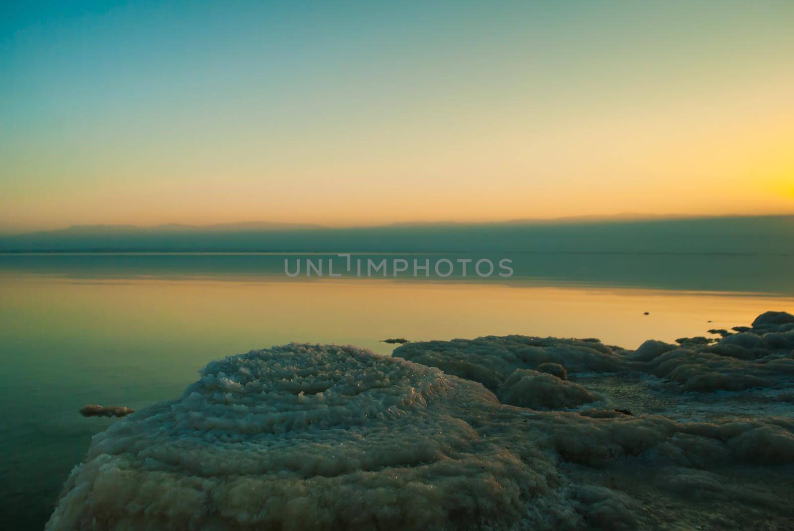 Beautiful sunrise at Dead Sea in Israel wih rocks of salt at foreground